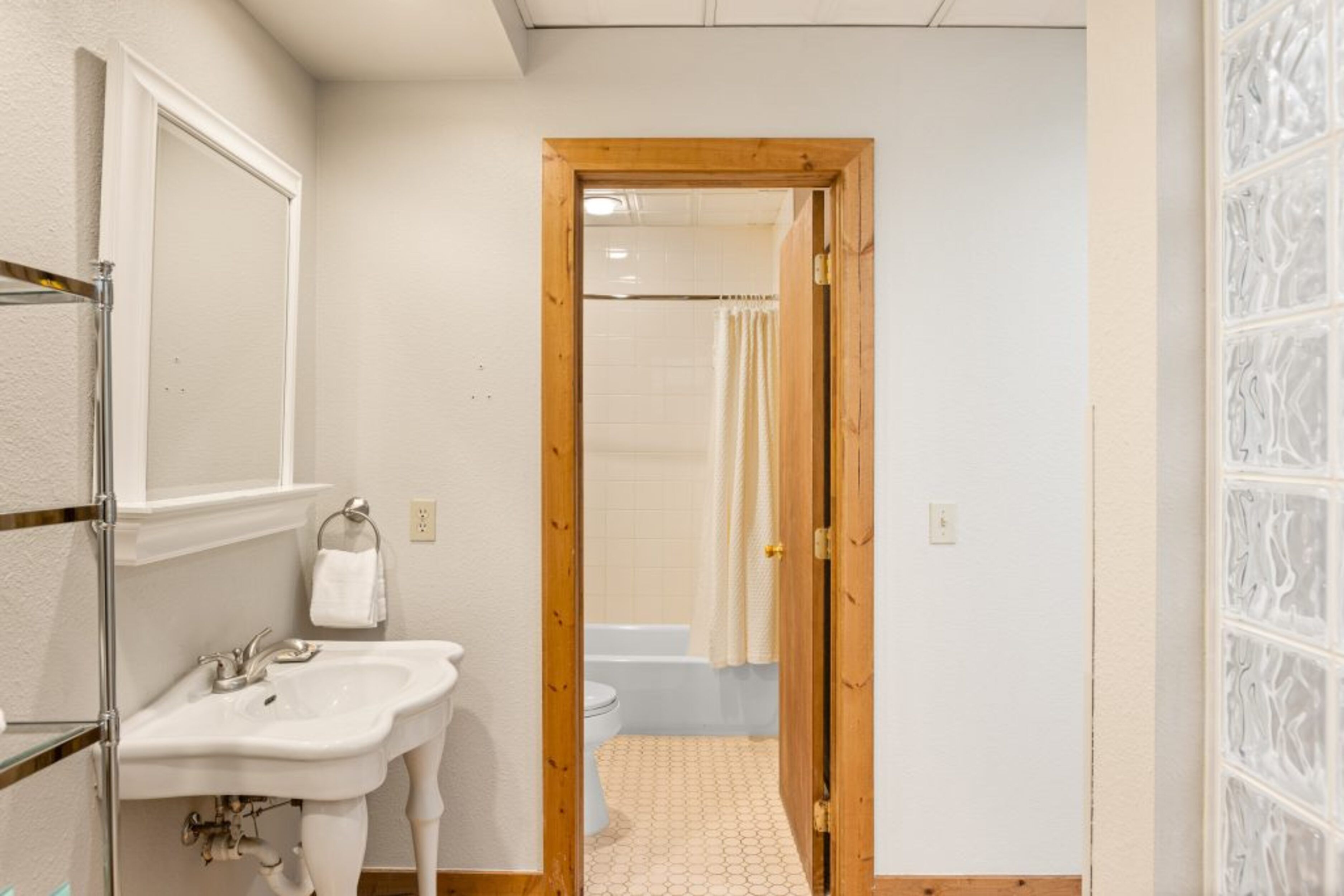 Un corridoio stretto che conduce a un bagno con lavandino, WC e vasca da bagno.