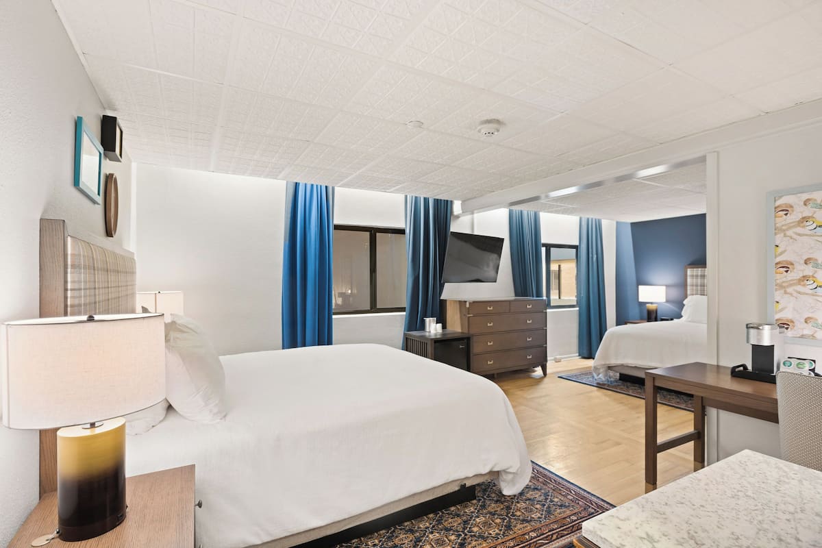 Una habitación de hotel con cama, escritorio, cómoda, televisor y baño.