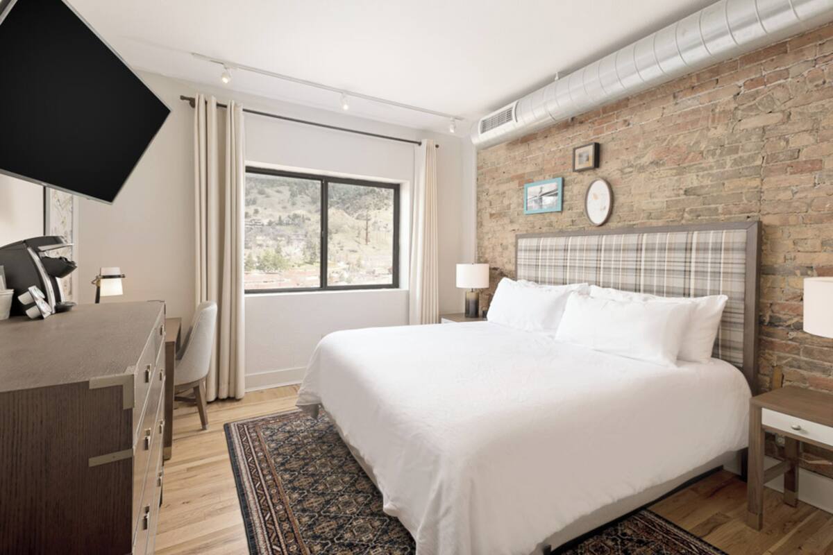 Una habitación de hotel moderna con una cama grande, un escritorio y una televisión.