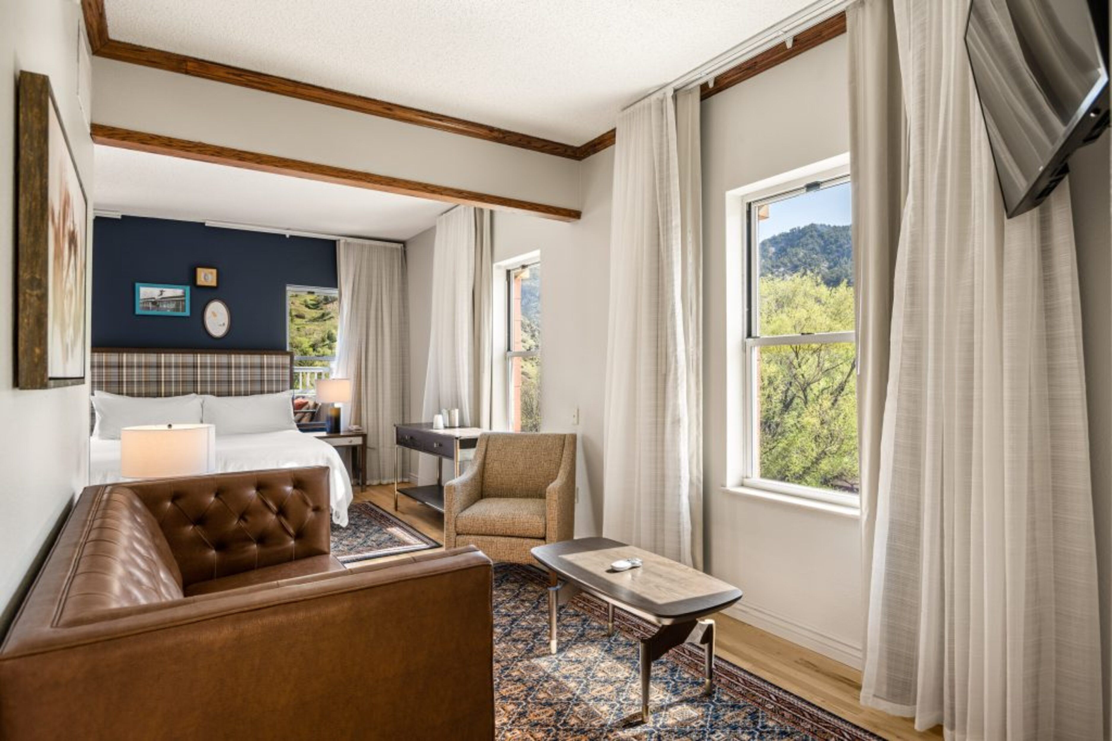 Habitación de hotel con cama, sofá, escritorio y vistas al exterior.