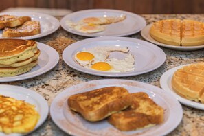 A variety of breakfast items including pancakes, eggs, and waffles on plates.