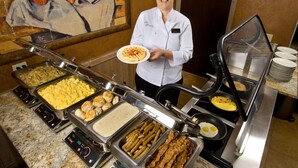 A buffet setup with various food items and a chef serving a plate.