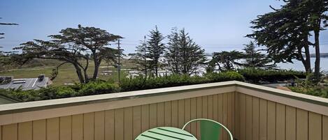 A balcony with a view of trees and a body of water.