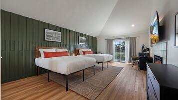 A modern hotel room with two beds, a fireplace, a TV, and a view of the outdoors.
