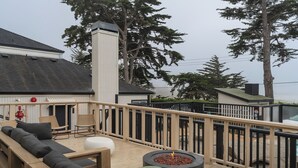 Eine Terrasse mit Feuerstelle, Sitzgelegenheit und Blick auf die umliegenden Bäume.
