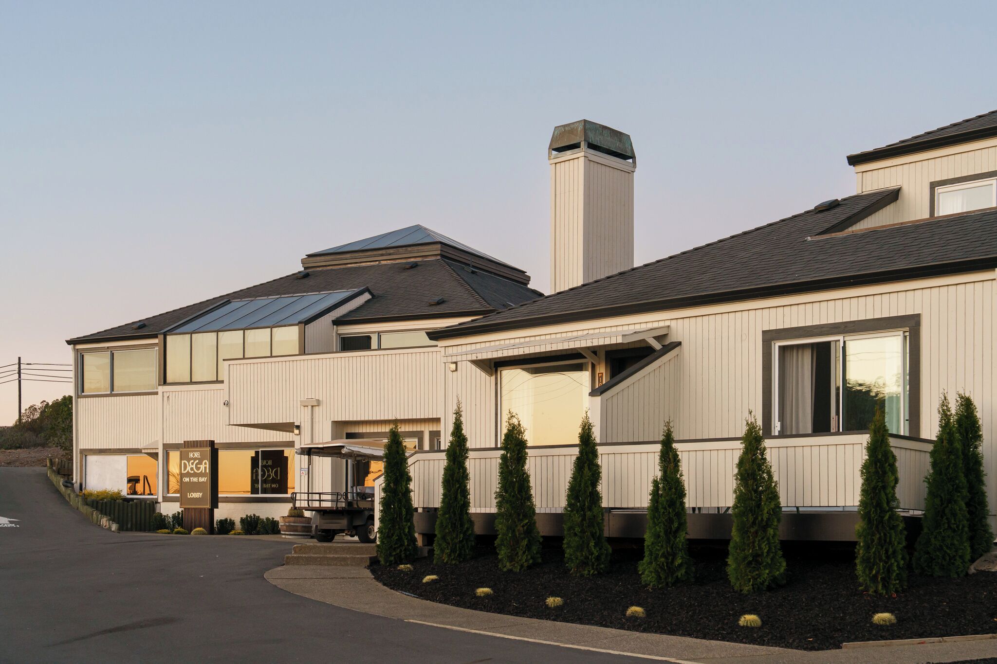 Ein modernes Hotel mit zweigeschossiger Bauweise, großen Fenstern und einer überdachten Außenfläche.
