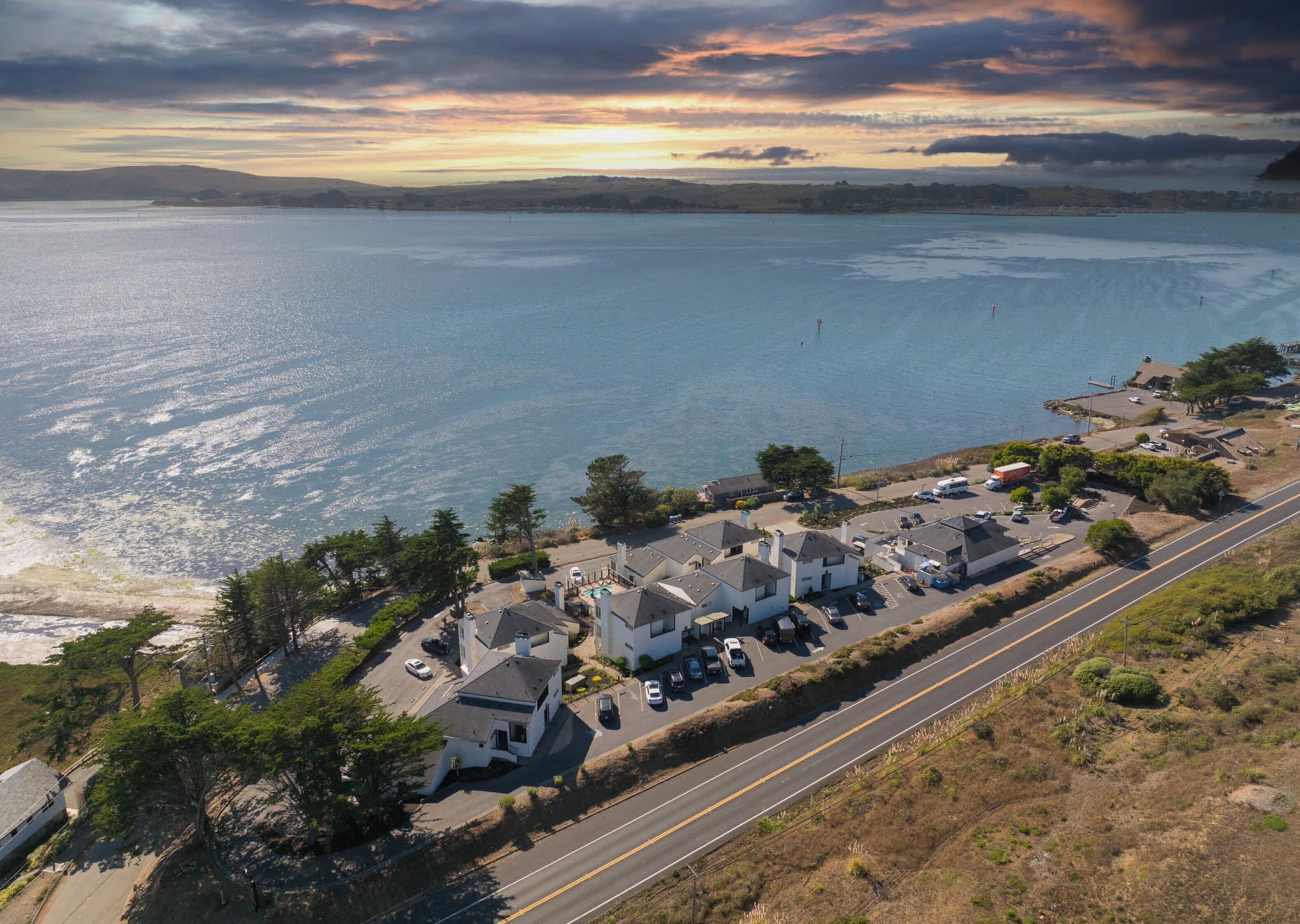 Vista aérea de una zona residencial costera con casas, una carretera y una playa.