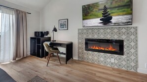 Ein modernes Wohnzimmer mit Kamin, Schreibtisch und bequemen Sessel.