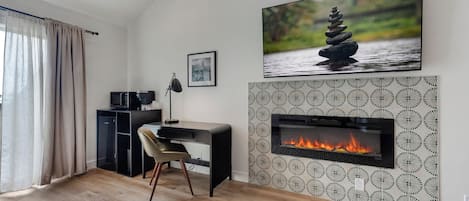 A modern living room with a fireplace, a desk, and a comfortable chair.