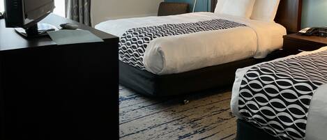 Una habitación de hotel con dos camas, un escritorio con computadora y una lámpara.