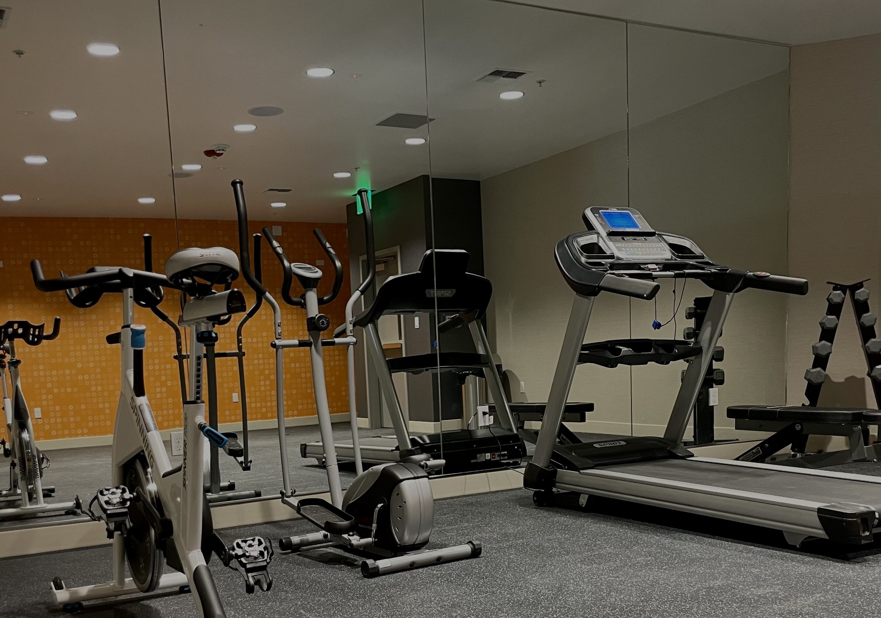 Une salle de sport équipée de divers appareils d’exercice, notamment des tapis de course, des vélos d’appartement et des appareils de musculation elliptique.