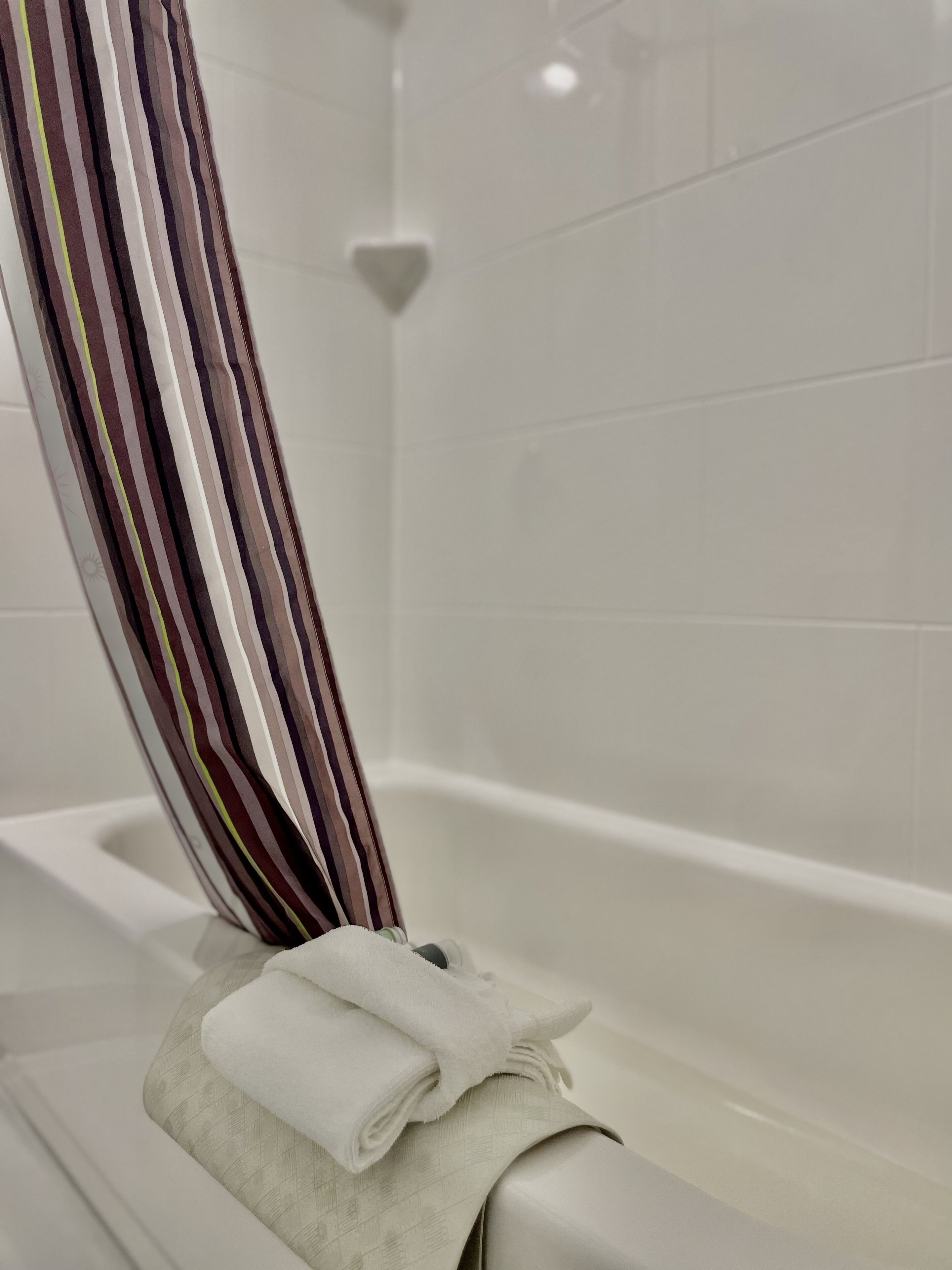 A bathtub with a striped towel and a folded towel.