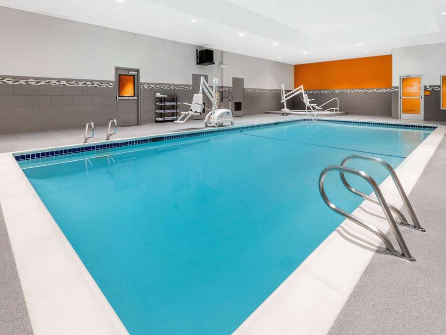 Una amplia piscina interior con agua cristalina azul, varias plataformas de salto y suelo de baldosas.