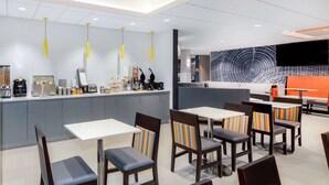 A modern restaurant with a counter, seating area, and a large wall mural. - La Quinta Inn by Wyndham Lynnwood (Lynnwood)