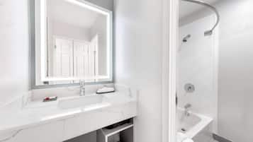 A modern bathroom with a white marble sink, a large mirror, and a shower area.