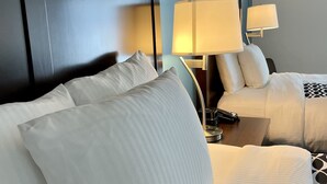 A hotel room with two beds, each with white linens and pillows, a bedside table with a lamp, and a dark headboard. - La Quinta Inn by Wyndham Lynnwood (Lynnwood)