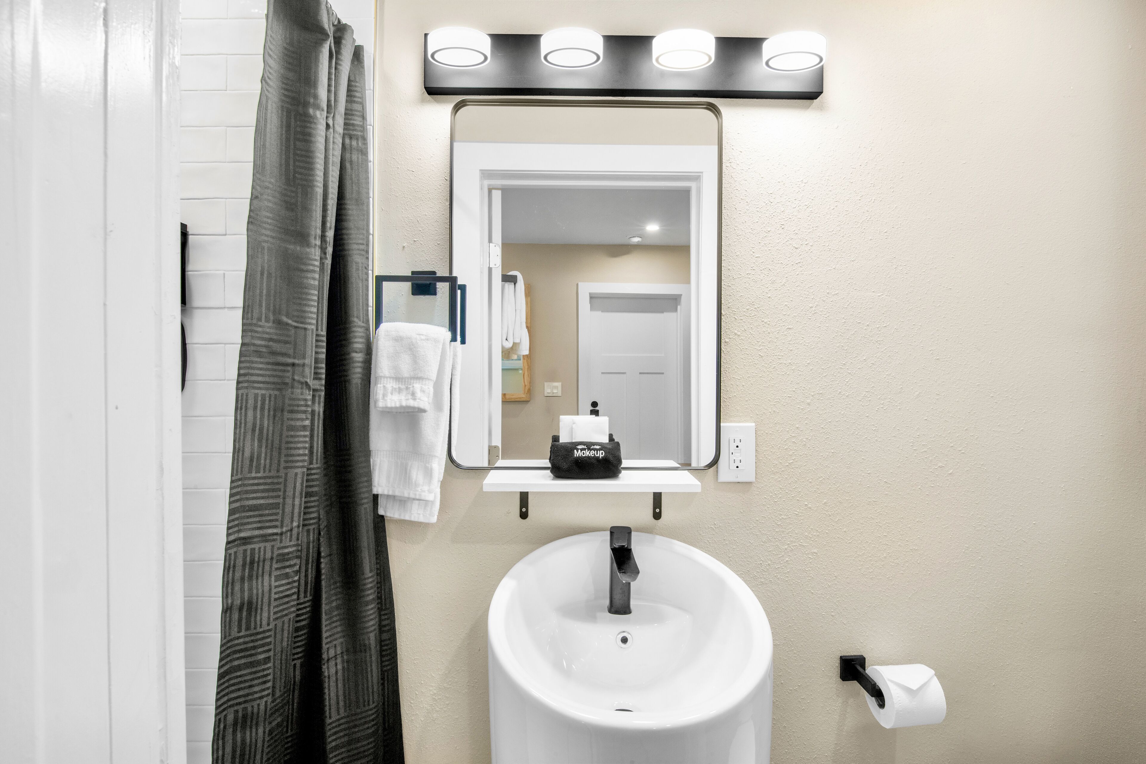 A bathroom with a white sink, a mirror, and a towel rack.