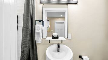 A bathroom with a white sink, a mirror, and a towel rack.