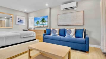 A modern hotel room with a bed, a sofa, a coffee table, and a large window.