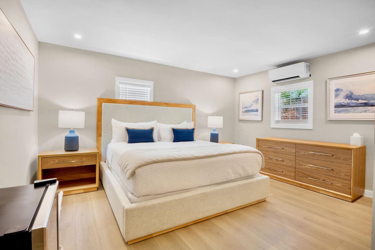 A bedroom with a bed, bedside tables, a dresser, and wall art.