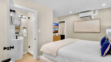 A modern bedroom with a large bed, a built-in sink, and a shower.