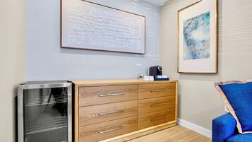 A modern room with a wooden cabinet, a refrigerator, and two framed artworks on the wall.