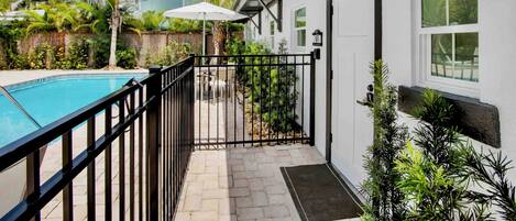 A residential property with a swimming pool, a covered patio, and a gated entrance.