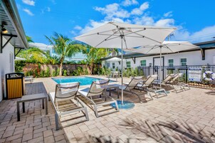 A poolside area with lounge chairs, umbrellas, and a pool.