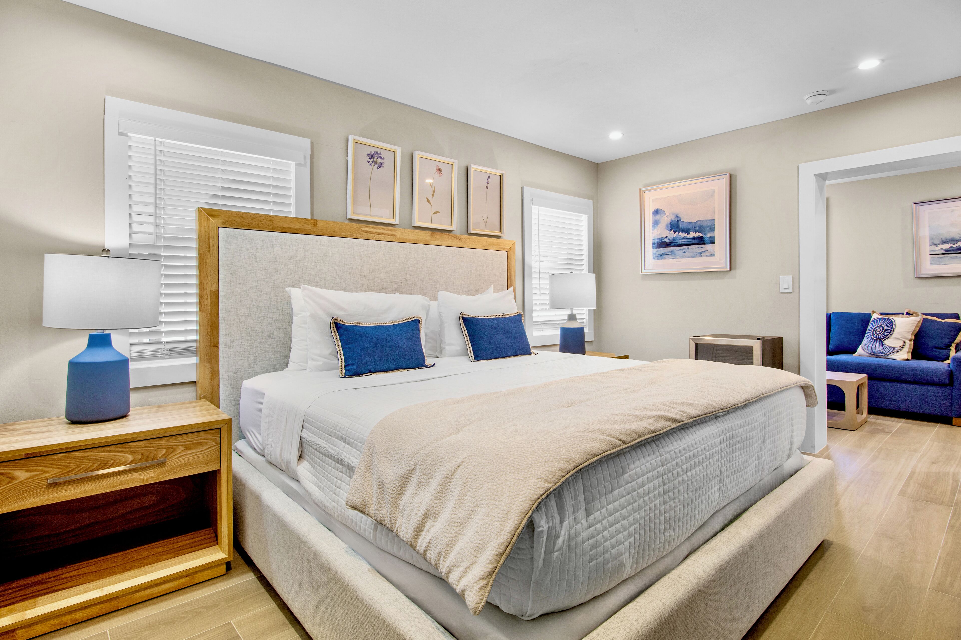 A bedroom with a large bed, a nightstand, a blue lamp, and a blue sofa.