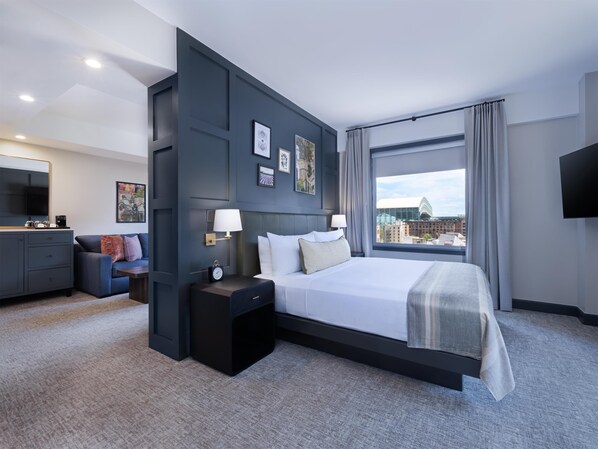 Una habitación de hotel moderna con una cama grande, un escritorio, una silla y un televisor.