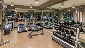 Una palestra con tapis roulant, ellittiche e un espositore di manubri.