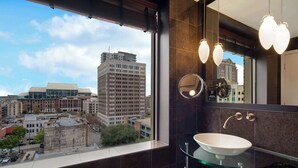 Une salle de bain moderne avec une grande fenêtre, un lavabo en verre et un miroir.