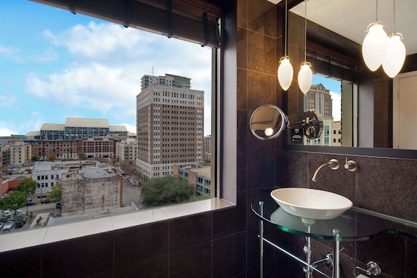 Une salle de bain moderne avec une grande fenêtre, un lavabo en verre et un miroir.