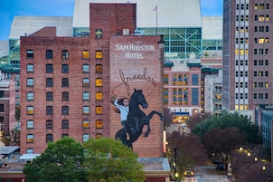 A brick building with a mural of a woman on a horse and the text "SAM HOUSTON HOTEL" and "freedom".