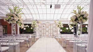 Un lieu de réception pour mariage doté d’une allée dégagée, de compositions florales blanches et d’un sol carrelé.