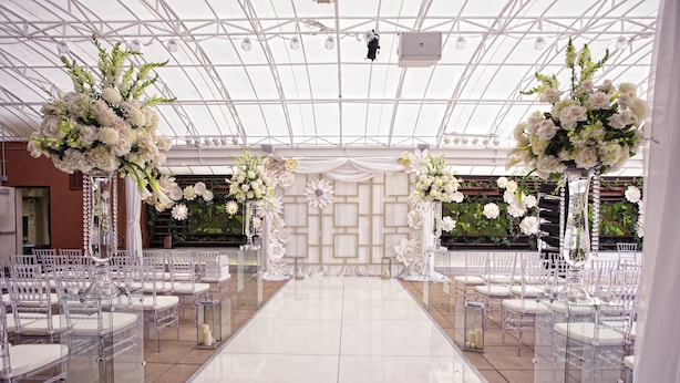 A wedding venue with a clear aisle, white floral arrangements, and a tiled floor. - The Sam Houston Hotel, Tapestry Collection by Hilton (Houston)