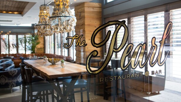 L’intérieur d’un restaurant avec une table en bois, des chaises et un lustre décoratif.