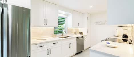 A modern kitchen with white cabinetry, stainless steel appliances, and a clean, minimalist design.