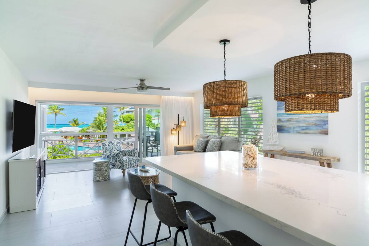 Cozinha moderna com uma ilha grande, banquetas e iluminação pendente.