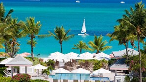 A resort with a pool, lounge chairs, umbrellas, and a view of the ocean. - Ocean Club East, Grace Bay Beach (Providenciales)
