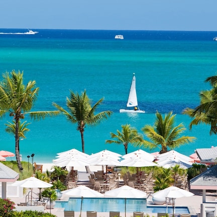A resort with a pool, lounge chairs, umbrellas, and a view of the ocean.