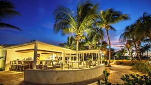 An outdoor bar area with seating, palm trees, and a stone pathway. - Ocean Club East, Grace Bay Beach (Providenciales)