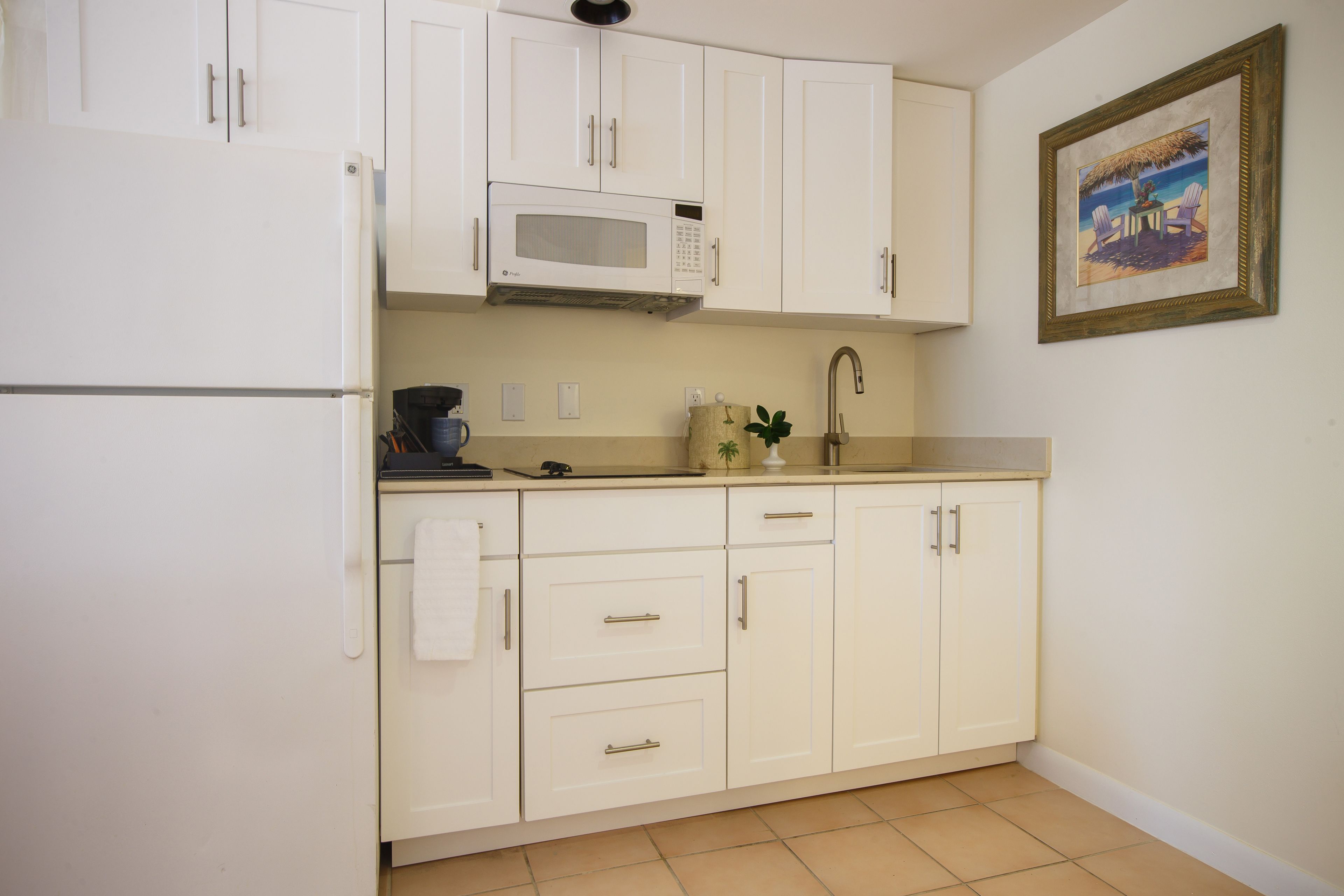 A compact kitchen with white cabinets, a microwave, and a sink.
