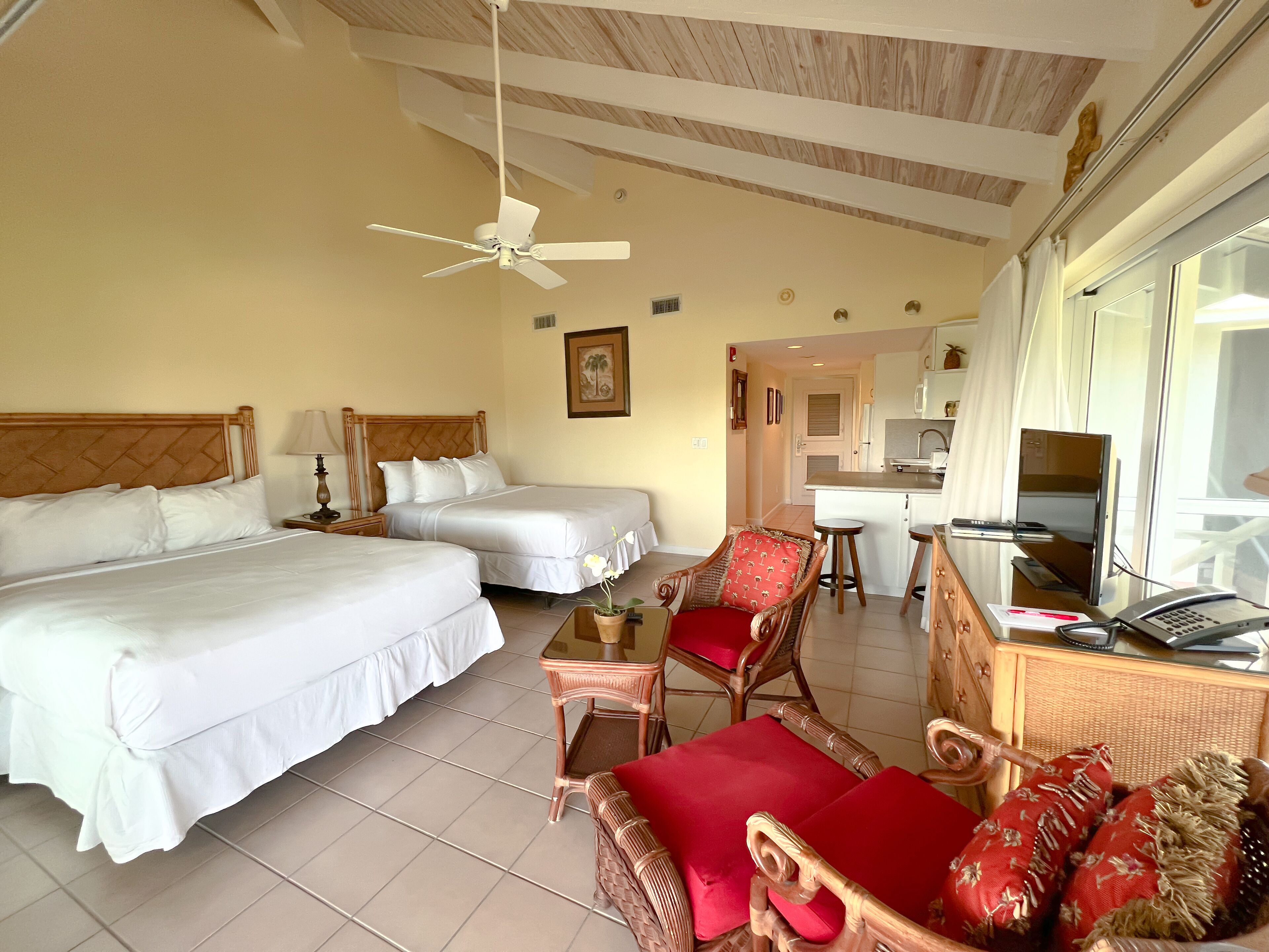 A hotel room with two beds, a dining area, and a kitchenette.