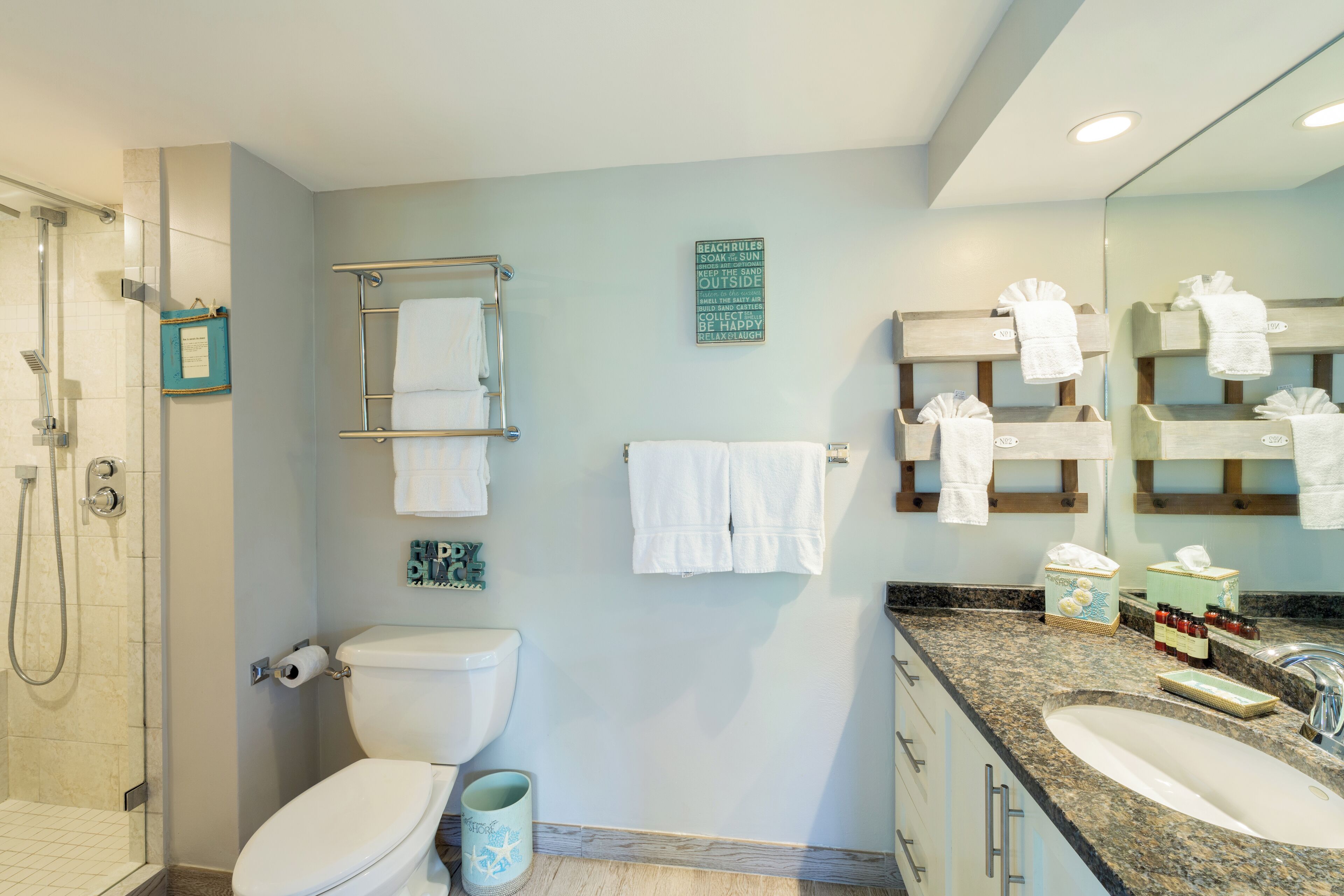 A bathroom with a shower, toilet, sink, and towel racks.