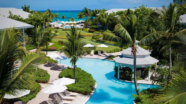 A resort with a central swimming pool, lounge areas, and a view of the ocean. - Ocean Club East, Grace Bay Beach (Providenciales)