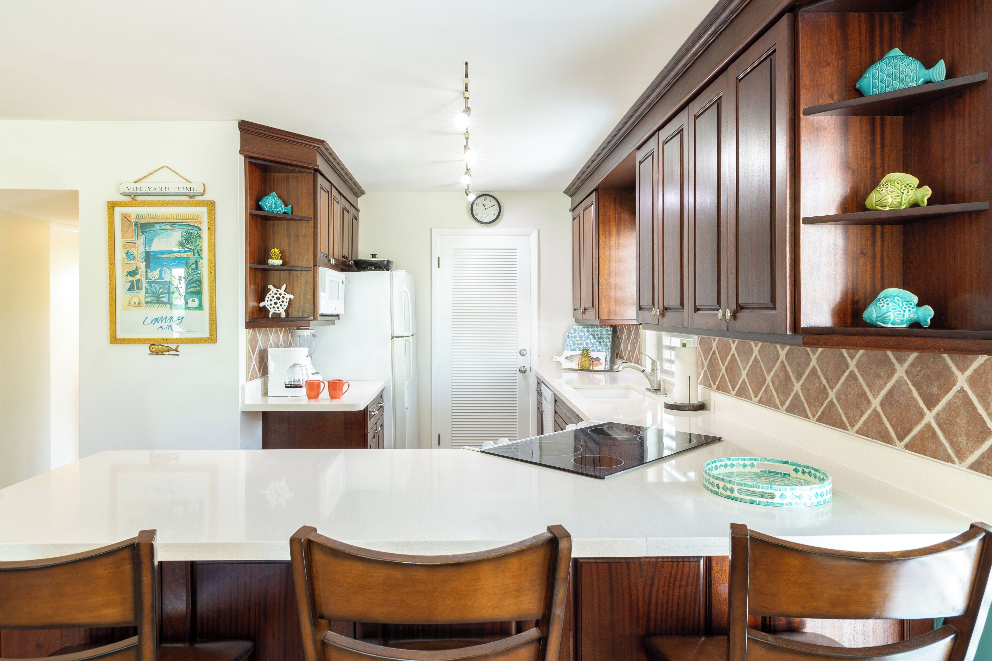 A kitchen with wooden cabinets, a white countertop, and a dining table with chairs.