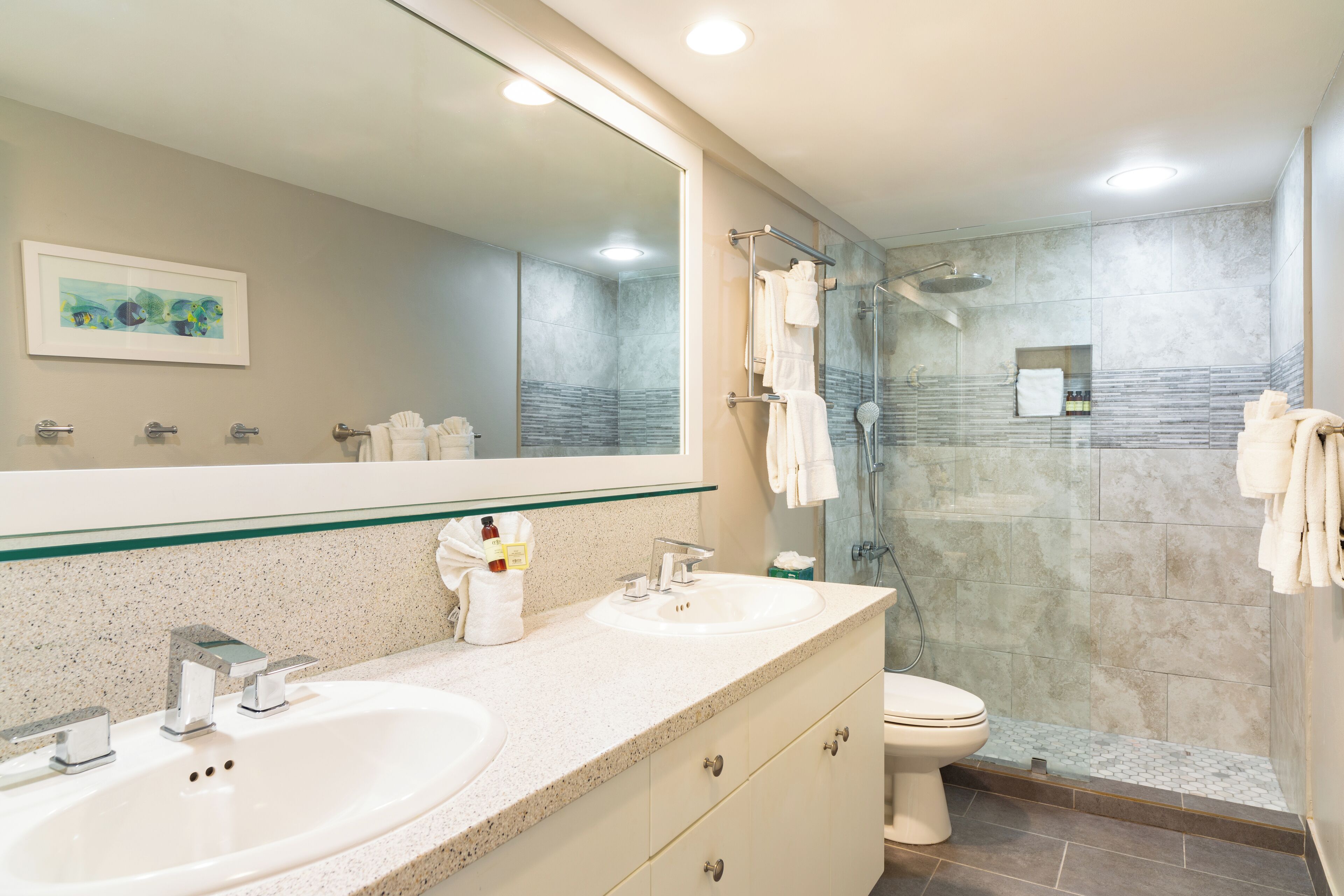 A bathroom with two sinks, a toilet, and a glass-enclosed shower.