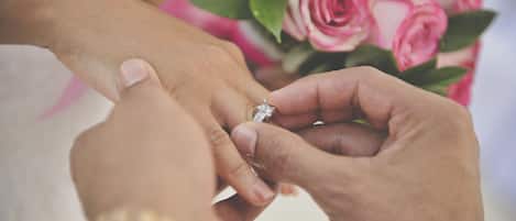 A close-up of hands exchanging a diamond ring.