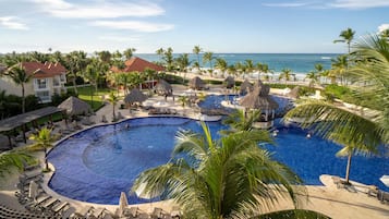 A resort with a large central pool, multiple smaller pools, and a beach view.